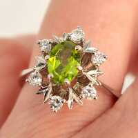 Vintage Schmuck in Gold - Annodazumal Antikschmuck: Eleganter Ring in Weißgold mit blütenförmigem Ringkopf, grünem Peridot in der Mitte, umgeben von Brillanten und zartem Blattdekor, 1960/70er Jahre
