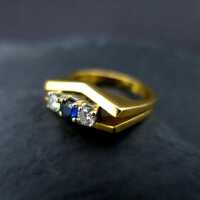 Elegant shaped ladys ring in 18 k gold with two diamonds and a deep blue sapphire