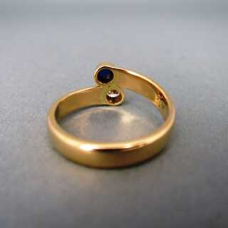Woman gold bypass ring with sparkly diamond and blue sapphire cabochon